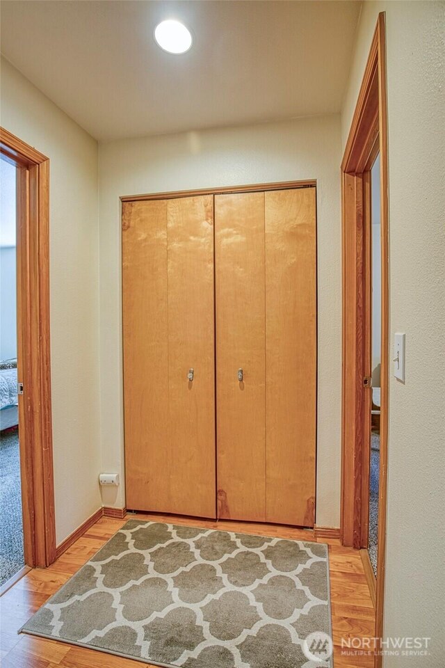 hallway featuring light wood finished floors, recessed lighting, and baseboards