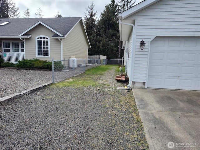 view of side of property with a garage, fence, and concrete driveway