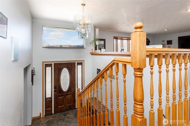 entrance foyer with stone finish floor and a notable chandelier