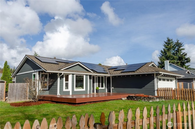 view of front of property featuring a fenced front yard, a front lawn, a wooden deck, and an attached garage