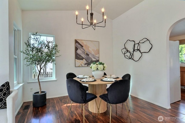 dining space featuring baseboards, arched walkways, lofted ceiling, dark wood-type flooring, and an inviting chandelier