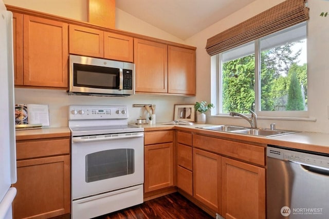 kitchen with dark wood-style floors, stainless steel appliances, light countertops, vaulted ceiling, and a sink