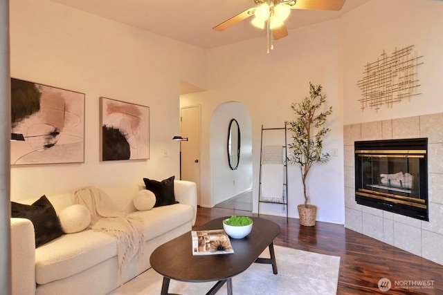 living room featuring ceiling fan, a fireplace, and wood finished floors