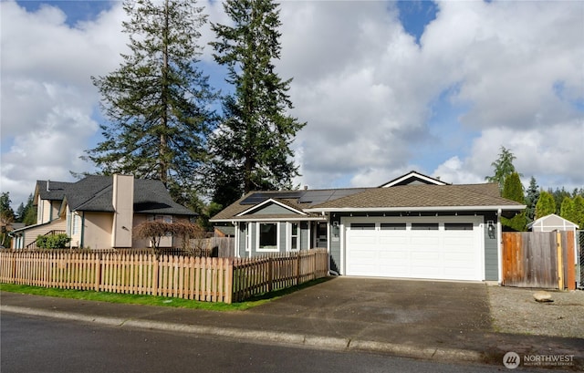 ranch-style home featuring a garage, a fenced front yard, solar panels, and concrete driveway