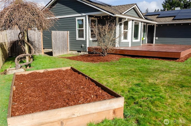 rear view of house with crawl space, roof mounted solar panels, a lawn, and a wooden deck