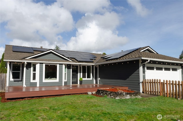 view of front facade featuring roof with shingles, an attached garage, fence, a deck, and a front yard