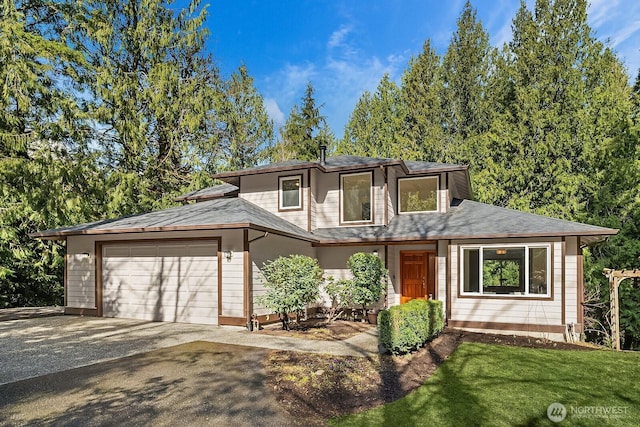 prairie-style house featuring a front yard, driveway, and an attached garage