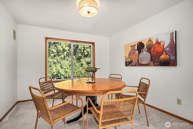 dining space featuring light carpet and baseboards