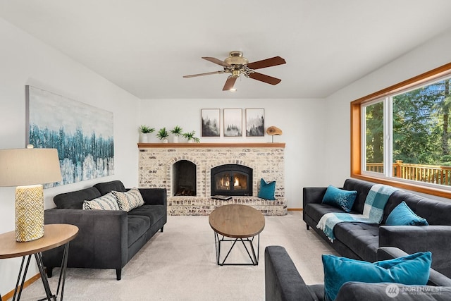 living area featuring light carpet, a fireplace, and a ceiling fan