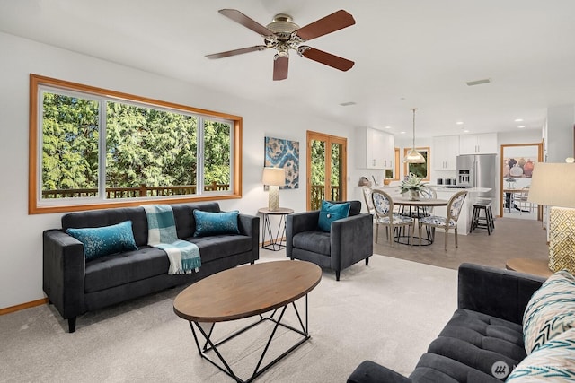 living area featuring baseboards, recessed lighting, a ceiling fan, and light colored carpet