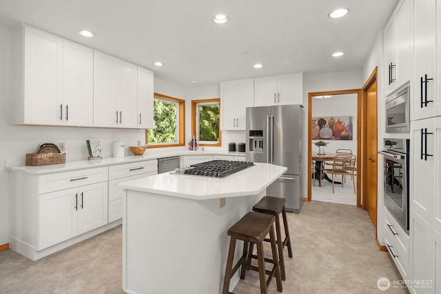 kitchen featuring stainless steel appliances, recessed lighting, light countertops, and a kitchen breakfast bar