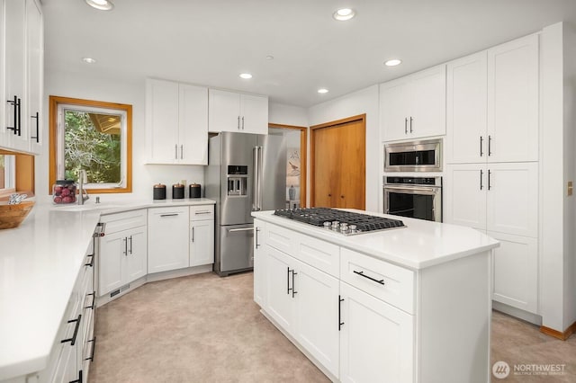 kitchen with white cabinets, a kitchen island, appliances with stainless steel finishes, a sink, and recessed lighting