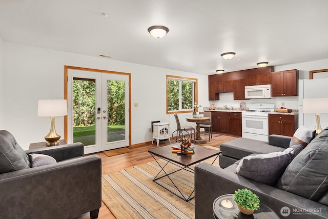 living area featuring light wood finished floors, baseboards, visible vents, and french doors