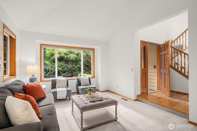 living room with visible vents, baseboards, light colored carpet, lofted ceiling, and stairs