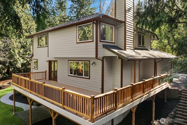 back of house with a shingled roof, a chimney, and a deck