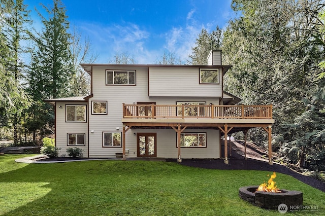 back of house featuring french doors, a yard, a chimney, a fire pit, and a wooden deck