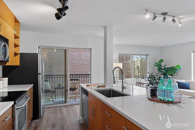 kitchen with a sink, wood finished floors, brown cabinetry, stainless steel appliances, and modern cabinets