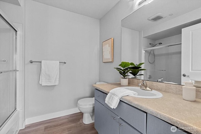 bathroom with vanity, toilet, wood finished floors, and baseboards