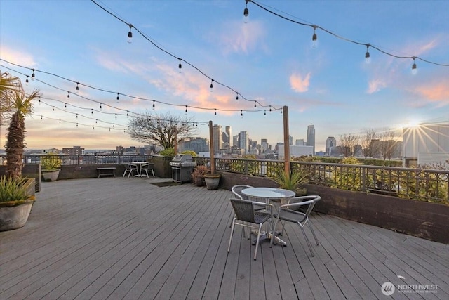 deck featuring a city view, area for grilling, and outdoor dining space