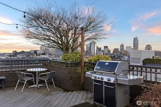 deck at dusk with a city view and area for grilling