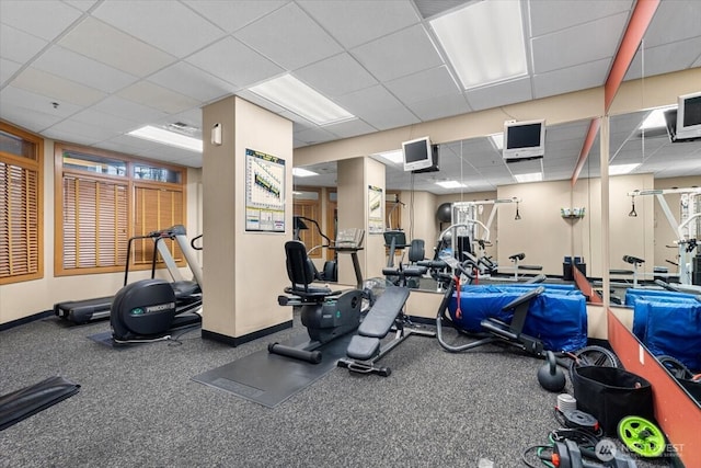 exercise room featuring a drop ceiling and baseboards