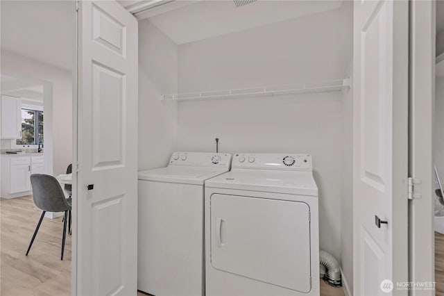 washroom with laundry area, light wood-type flooring, and washing machine and clothes dryer