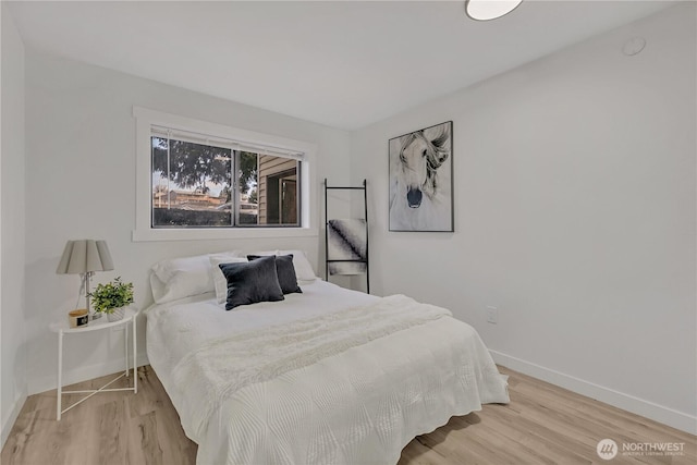 bedroom with light wood finished floors and baseboards