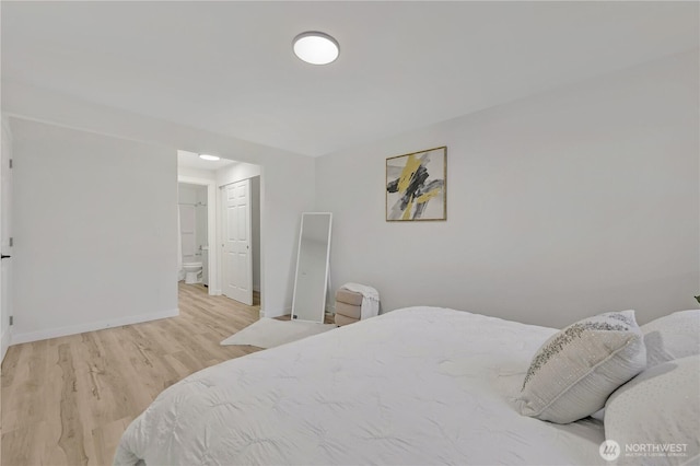 bedroom with light wood-style floors, baseboards, and connected bathroom