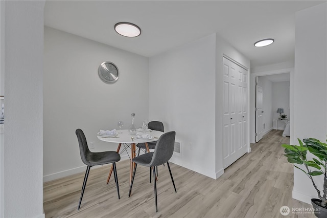 dining space with light wood-style flooring, visible vents, and baseboards