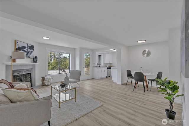 living area with light wood finished floors, baseboards, and a tile fireplace