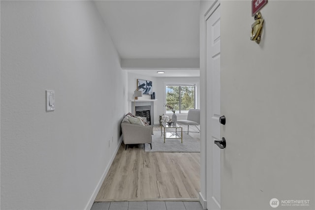 doorway with a fireplace, wood finished floors, and baseboards