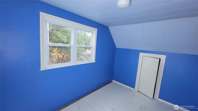 additional living space featuring concrete flooring, lofted ceiling, and baseboards