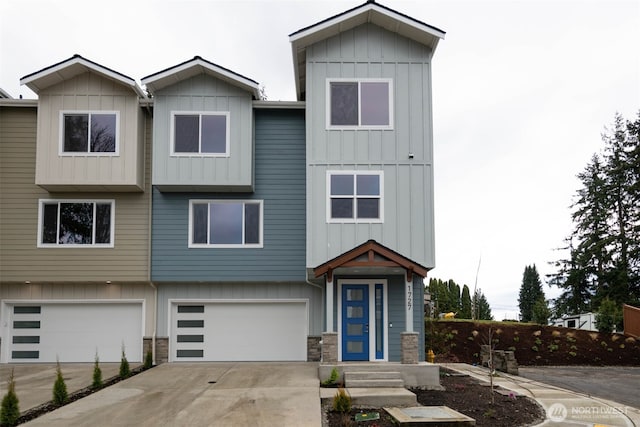 townhome / multi-family property with a garage, stone siding, board and batten siding, and concrete driveway