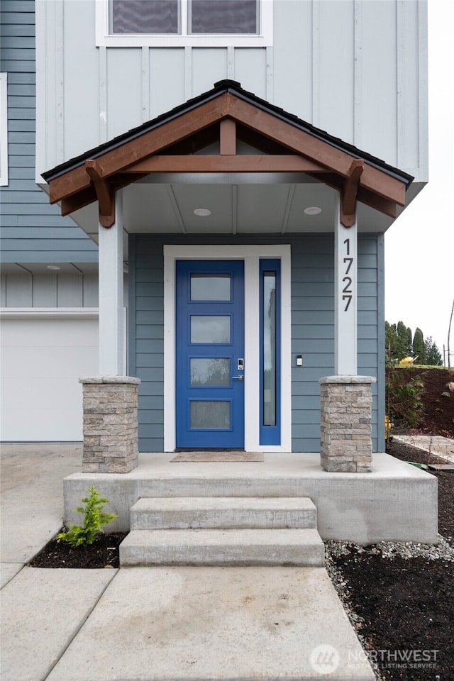 entrance to property featuring board and batten siding, concrete driveway, covered porch, and an attached garage