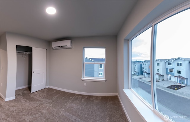 bedroom featuring baseboards, dark colored carpet, a closet, and a wall mounted AC