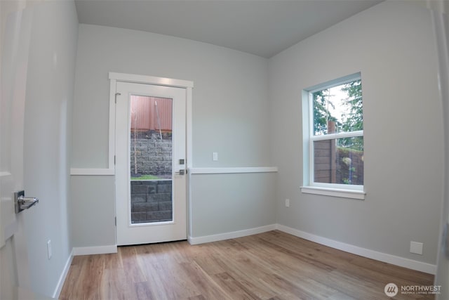 doorway featuring baseboards and wood finished floors