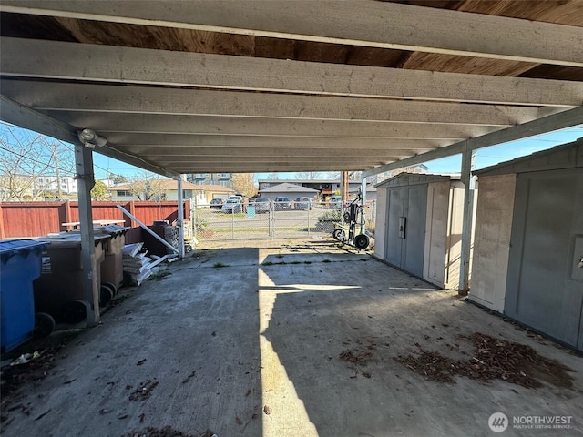 view of patio featuring an outbuilding, a carport, a shed, and fence