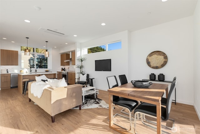 living room featuring recessed lighting, baseboards, and light wood finished floors