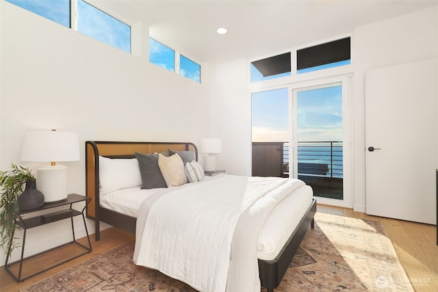 bedroom with access to outside, multiple windows, wood finished floors, and recessed lighting