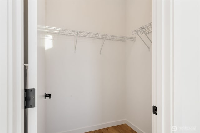 walk in closet with light wood-style flooring