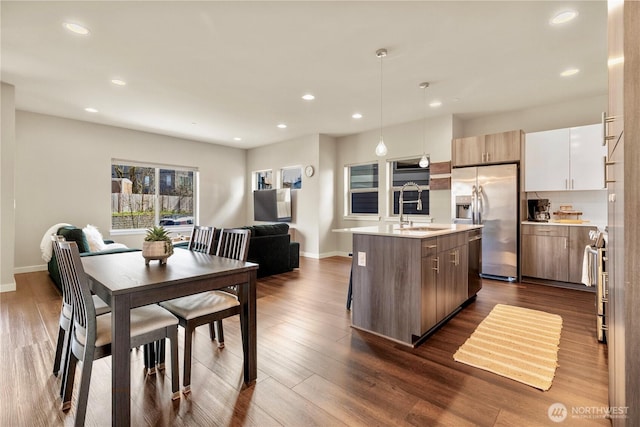 kitchen featuring a kitchen island with sink, stainless steel appliances, a sink, dark wood-style floors, and modern cabinets