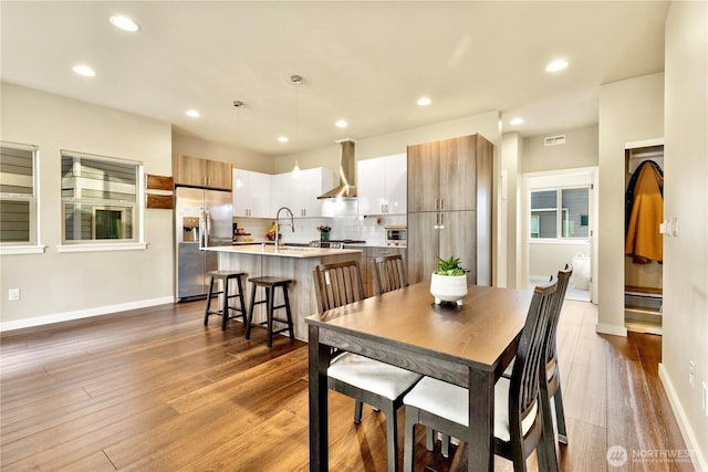 dining room with baseboards, wood finished floors, and recessed lighting