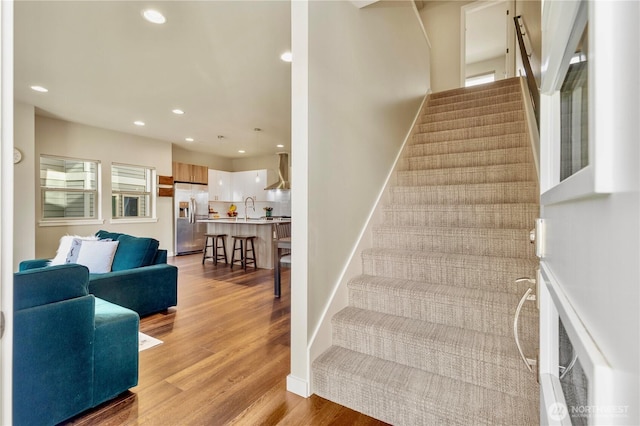 staircase with baseboards, wood finished floors, and recessed lighting