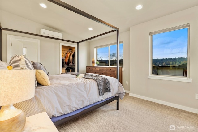 bedroom with baseboards, a wall unit AC, carpet, a walk in closet, and recessed lighting