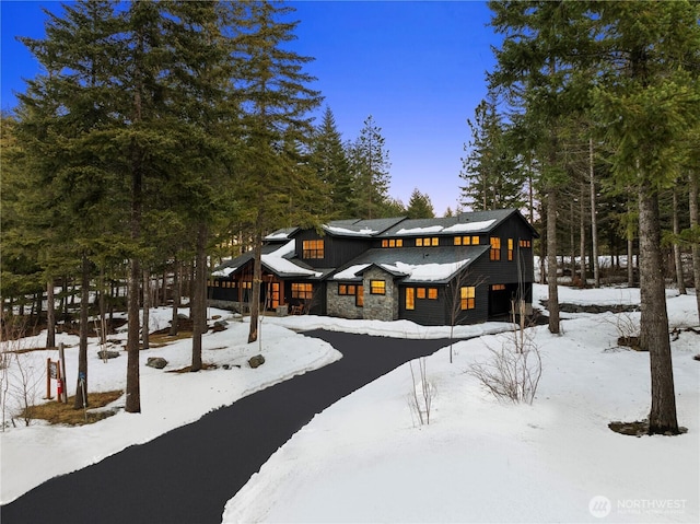 view of front of property featuring a garage, stone siding, and aphalt driveway