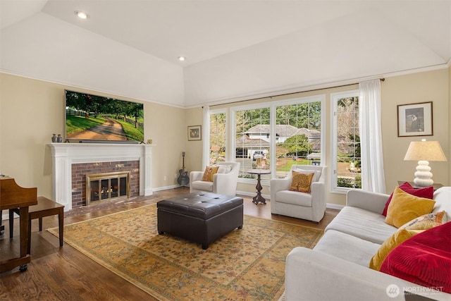 living room with baseboards, wood finished floors, vaulted ceiling, a fireplace, and recessed lighting