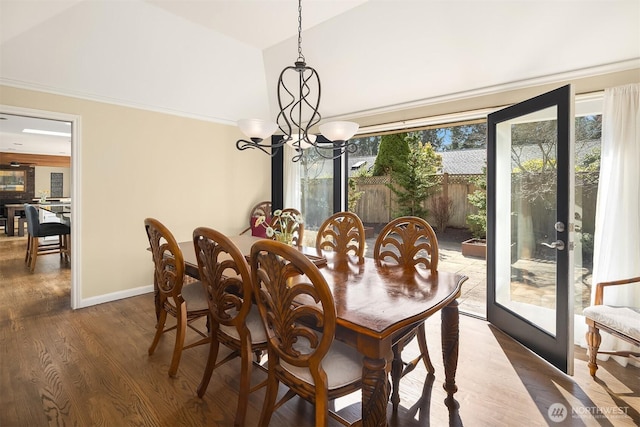 dining area featuring baseboards, lofted ceiling, dark wood-type flooring, crown molding, and a notable chandelier