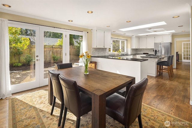 dining area with recessed lighting, a skylight, ornamental molding, french doors, and dark wood finished floors