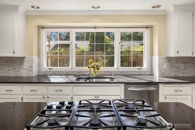 kitchen with dark stone counters, stainless steel appliances, a sink, and white cabinetry