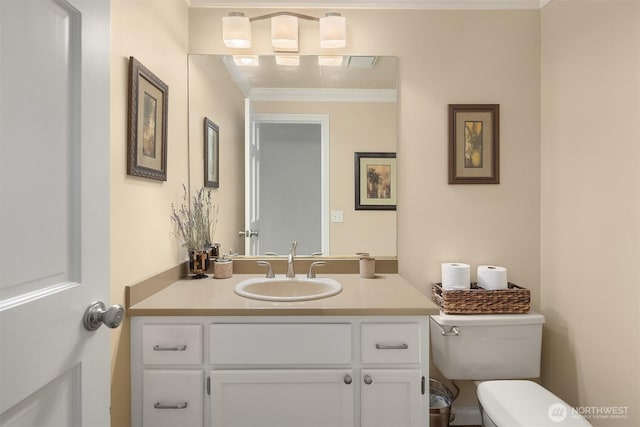 half bathroom with vanity, toilet, and crown molding